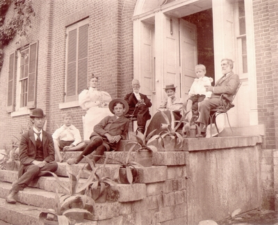 Several adults and children sitting on porch steps