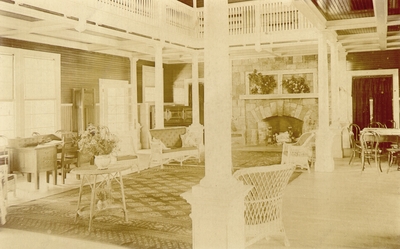 Large open two-story room decorated with stone fireplace and living room furniture printed on postcard