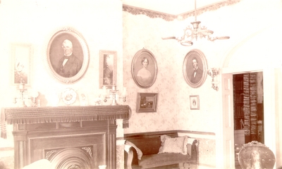 Parlor with fireplace and three portraits on walls