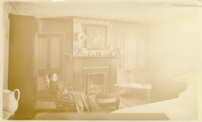 Mrs. M.C. Lyle seated near fireplace