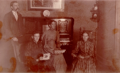 Lyle family home; Charles Nourse Lyle, Lizzie Lyle, Helen Lyle, and Mrs. M.C. Lyle with piano in background