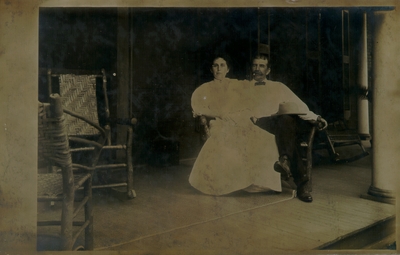 Middle-aged couple seated in wooden loveseat on porch; variant of #190