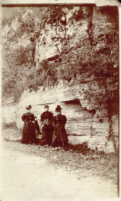 Lizzie Lyle, Helen Lyle, and another woman wearing full black outfits in front of rock cliff