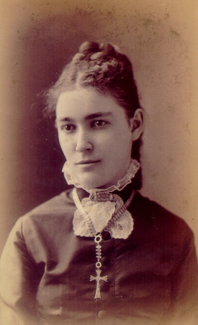 Young woman smiling, wearing black dress and cross necklace; Western Female Seminary