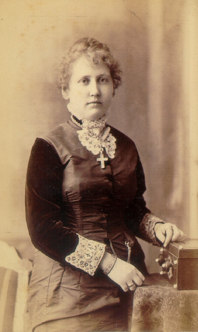Young woman wearing dark dress with dark velvet sleeves and many pieces of jewelry; Western Female Seminary