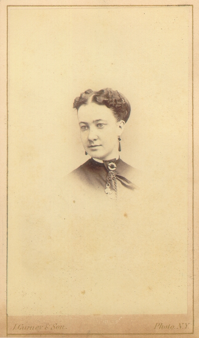 Woman with hair up and unusually wide part; Light eye color and dark clothing
