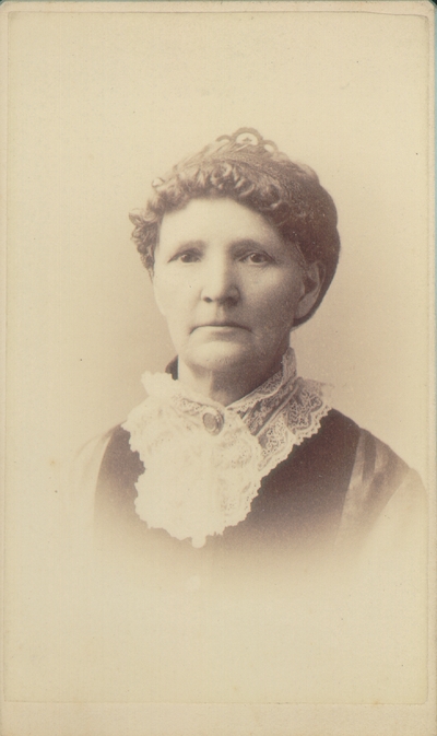 Woman with curly hair done up, wearing outfit with large white lace collar