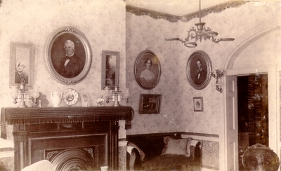 Elaborate room with fireplace and three portraits on the walls