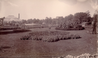 Well trimmed garden with several spectators; Large building with curved ceiling in background