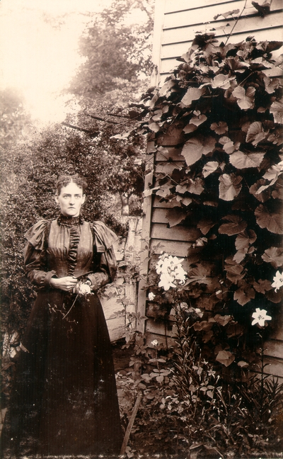 Helen Lyle standing in garden in front of fence