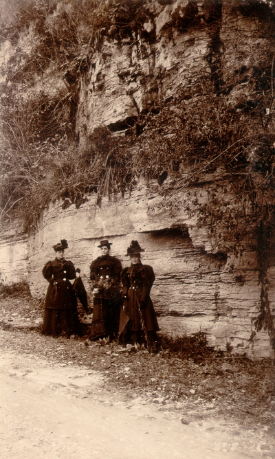 Lizzie Lyle, Helen Lyle, and another woman dressed all in black in front of rock wall
