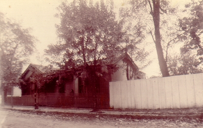 Small house off of street with woman on porch