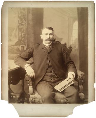 Unidentified man in chair, reading book