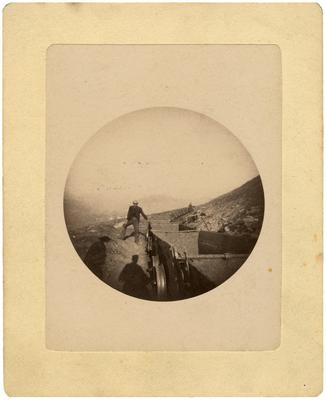 Unidentified man standing by railroad mining cars; loose in front of album