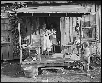 Miners' wives and children on the front porch of a typical, fifty-year-old house.  Four Mile, Bell County, KY. 9/4/46