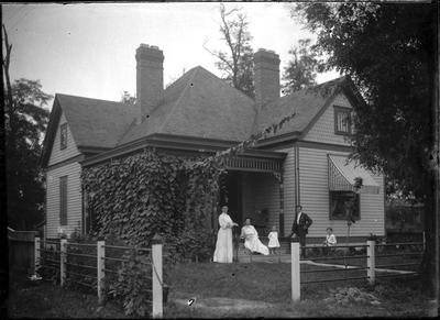 Family in front of a house;                          Adams Negative handwritten on envelope