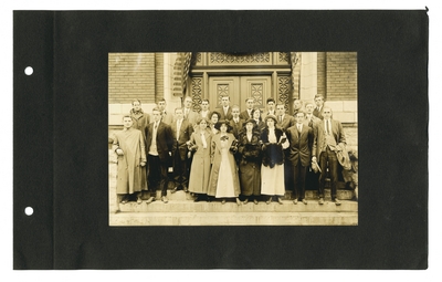 Group portrait of male and female students on steps in front of building