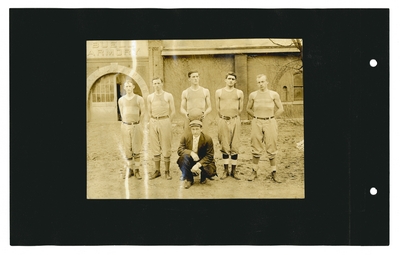 Group portrait: 5 members of basketball team with coach in front of Buell Armory