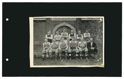 Group portrait: basketball team with coach in front of Buell Armory