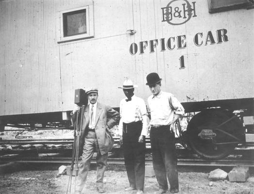 Louis E. Nollau and two unidentified men posing in front of B&H Railroad office car number 1, n.d