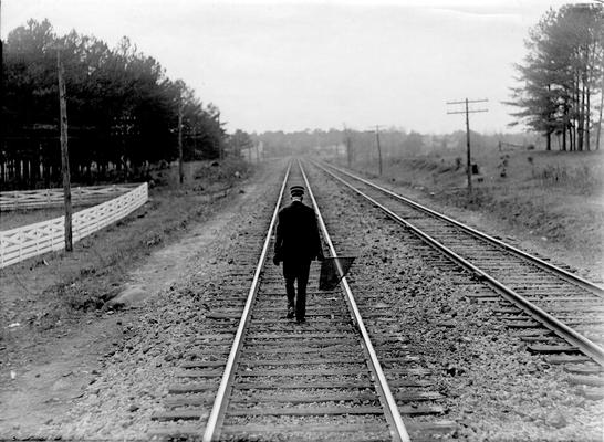 Man walking on tracks with flag