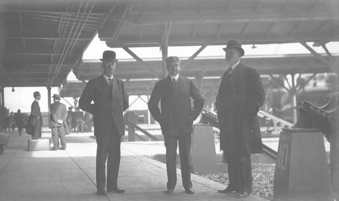 Three men standing in station near track 10