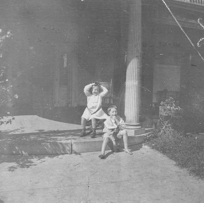 Young girl and young boy sitting on front steps of house