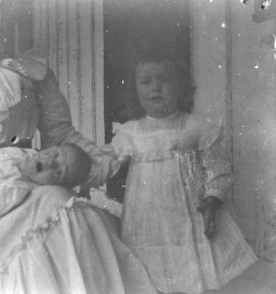 Young girl standing and infant in woman's lap