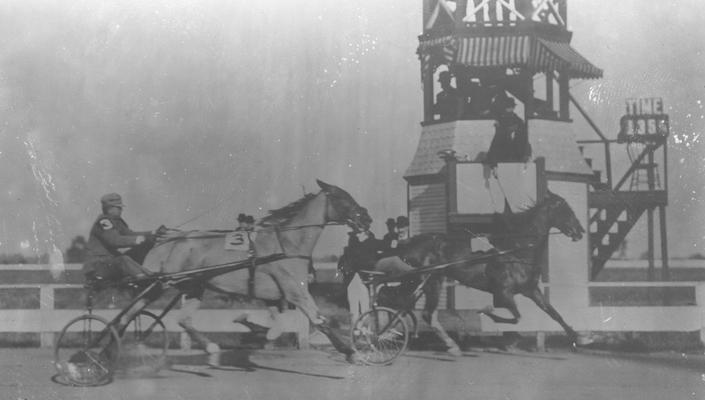 Judge's stand, two harness racers passing judge's stand, 