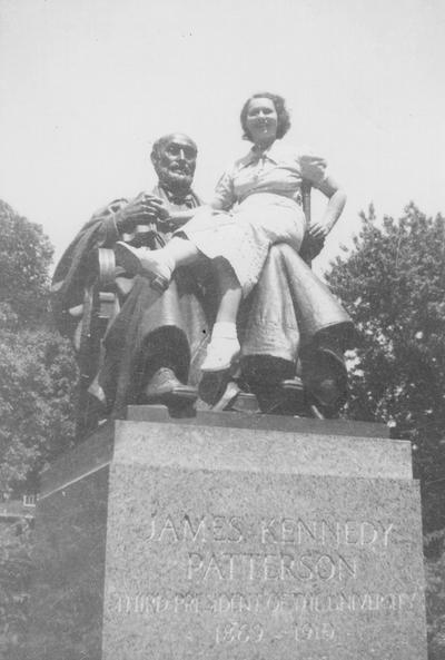 Unidentified woman seated on President James K. Patterson Memorial beside Administration Building