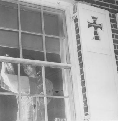 Unidentified woman student, hanging laundry at her dormitory or house window