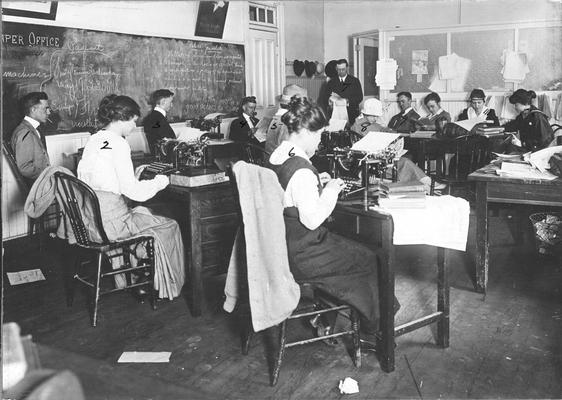 School of Journalism, women and men students in typing class and Professor Enoch Grehan, standing