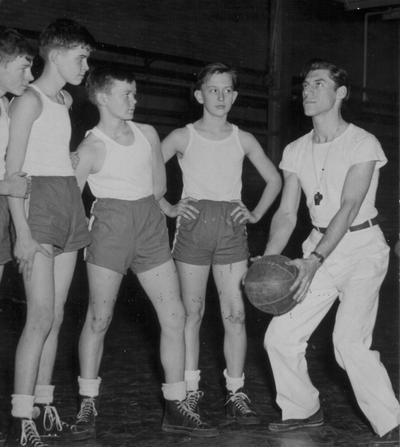 Coaching four students concerning basketball in gym class