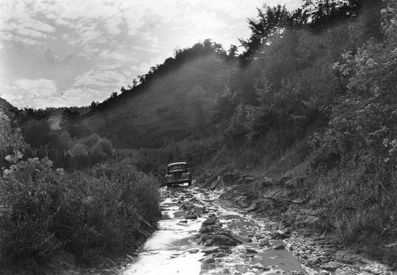 Car driving along rocky creek