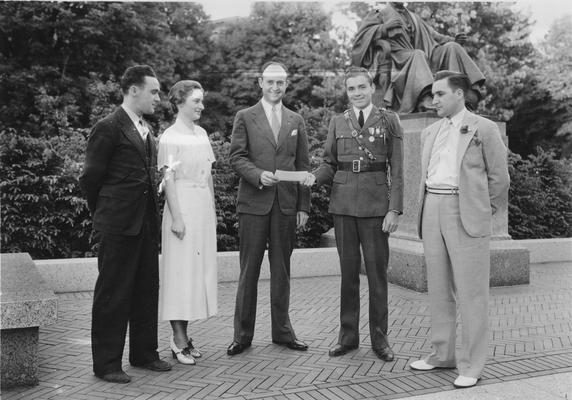 Alumni, four men, one woman, presentation of a check