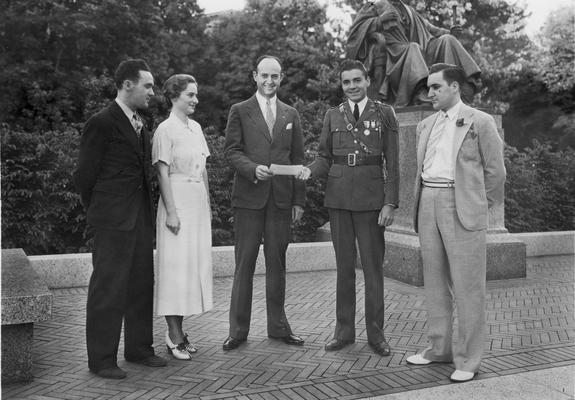 Alumni, four men, one woman, presentation of a check