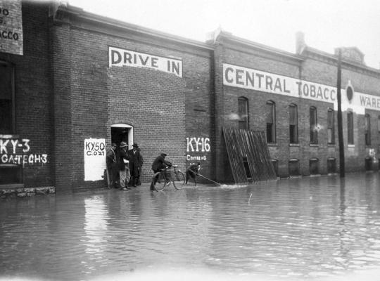 Several men standing in front of flooded Central Tobacco Warehouse