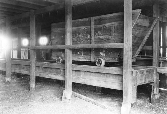 Possibly the inside of a barn with a wooden cart on a wooden track