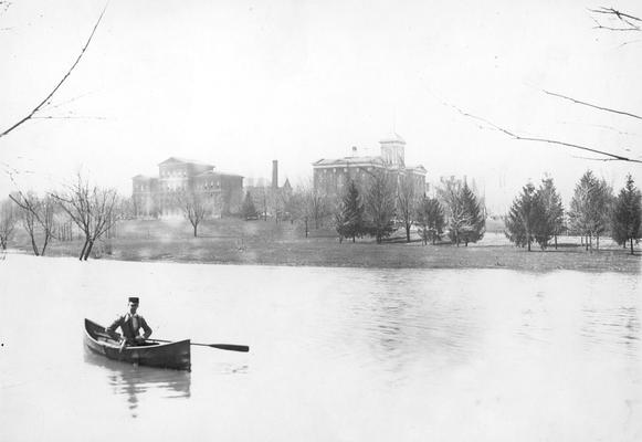 Scene of the lake and man in canoe, White Hall and Administration Building with tip roof on cupola, circa 1897 - 1903