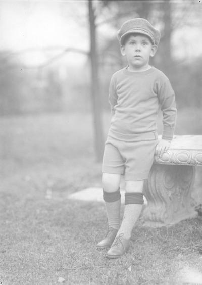 Boy leaning against a stone bench