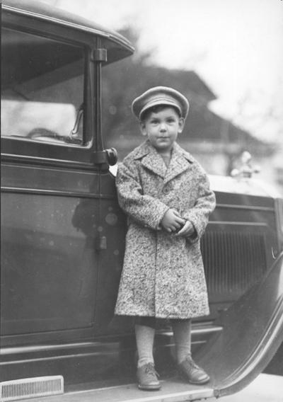 Boy standing beside a car