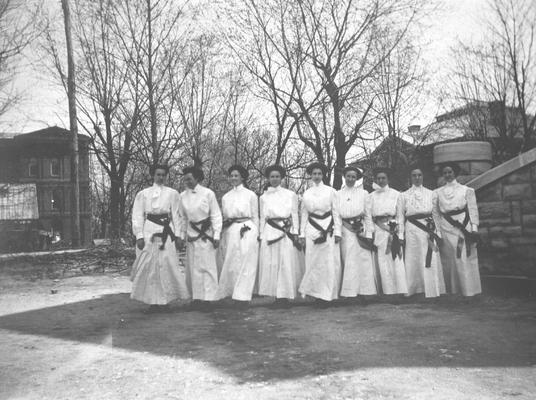 Students dressed in white standing in front of buildings, 1910, White Hall, Carnegie Library, and Miller Hall steps to the right