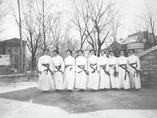 Students dressed in white standing in front of buildings, 1910, White Hall, Carnegie Library, and Miller Hall steps to the right