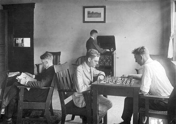 Two men playing chess, one man reading, and the other playing a phonograph record