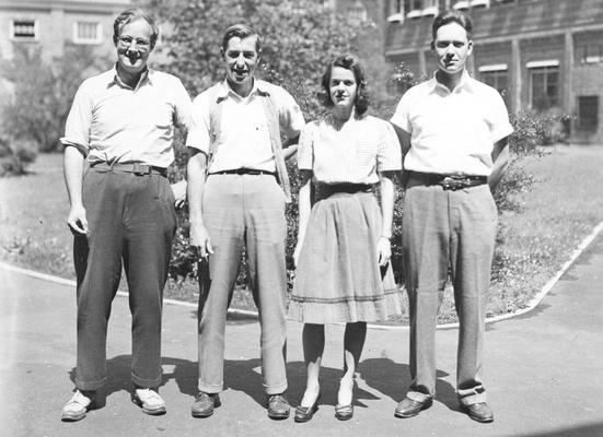 Men and a woman standing in front of a building, circa 1940