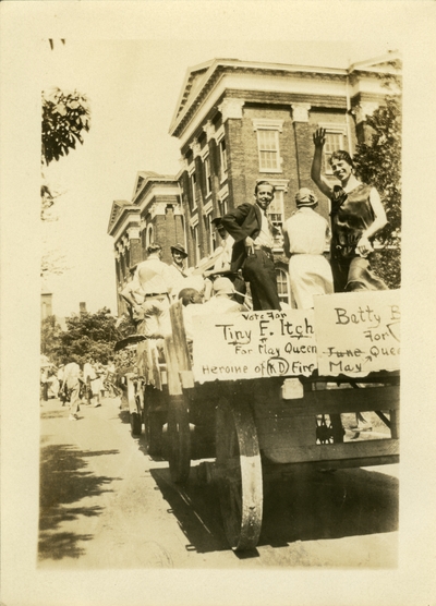 Men and women on a wagon float as part of a parade.  Sign on float reads 