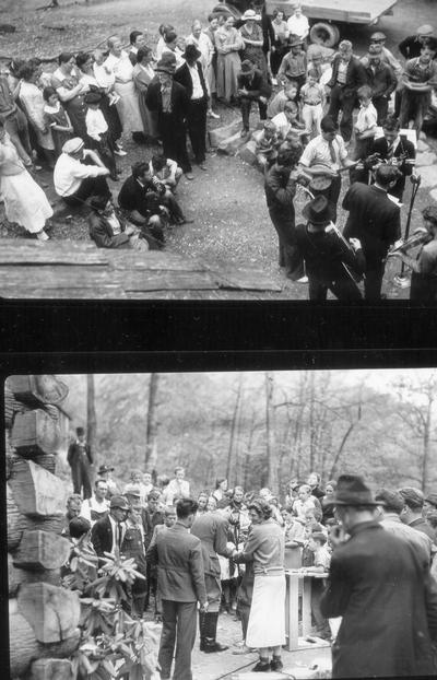 Bluegrass band playing around a CBS microphone in front of crowd; people watching man at microphone