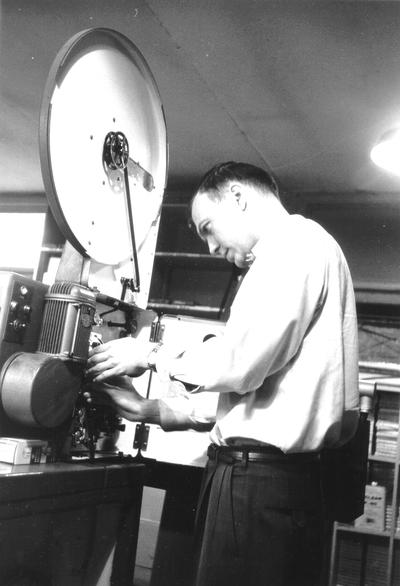 Man threading film in film projector
