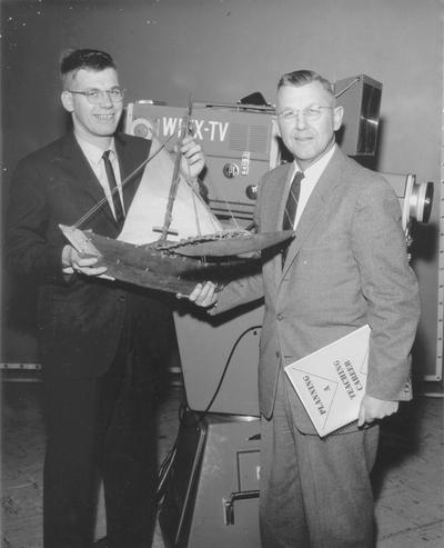 Student and teacher standing in front of WLEX-TV studio camera looking at wooden ship, John P. Malick (Dr. Ellis Hartford)