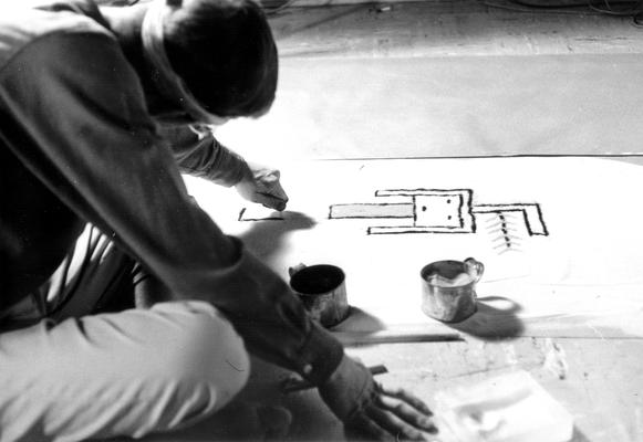 Dr. Doug Schwartz recreating artwork of indigenous peoples of the southwest on the floor of studio